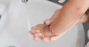 Un niño de madre de día se lava las manos